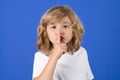 Kid with show no talk gesture. Boy with shows shh sign. Be quiet. Hush dont tell. Child put finger to lips mouth, ask