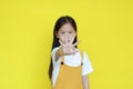Kid show warning expression isolated on yellow background. Asian little girl doing stop sing with palm of hand. Selective focus at