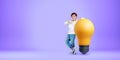 Kid showing thumb up standing near big lightbulb on empty purple background
