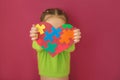 Kid shows a big heart made of colorful puzzles for autism Day Royalty Free Stock Photo