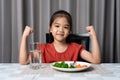 Kid shows strength of eats vegetables and nutritious food Royalty Free Stock Photo