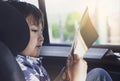 Kid siting on car seat and reading a book, Little boy sitting in the car in child safety seat, Portrait of toddler entertaining Royalty Free Stock Photo