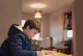 Kid siting on table doing homework,Child boy holding black pen writing on white paper,Young boy practicing English words at home.