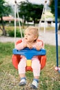 Kid sits on a swing in the playground and looks away Royalty Free Stock Photo