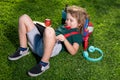 Kid sitting on grass with tablet in the park. Outdoor school. Smiling boy hold tablet computer. School, education Royalty Free Stock Photo