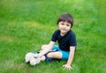 Kid sitting on grass using tablet for his homework in the garden on spring, Child boy playing  teddy bear toy in the park in sunny Royalty Free Stock Photo