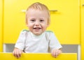 Kid sitting inside yellow opened kitchen box