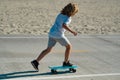 Kid skateboarder ride a skateboard on street. Child in a summer city. Little child, toddler boy riding skateboard in the