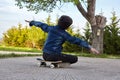 Kid skateboarder sitting on his skateboard and feels happy.