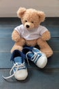 Baby shoes and teddy bear on blue wooden floor background Royalty Free Stock Photo