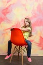 Kid or small smiling girl sitting on orange chair Royalty Free Stock Photo