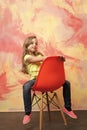 Kid or small smiling girl sitting on orange chair Royalty Free Stock Photo