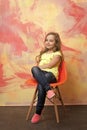 Kid or small smiling girl sitting on orange chair Royalty Free Stock Photo