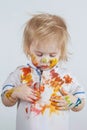 The kid smears paint on the face and a T-shirt. Children`s pranks