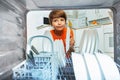 Kid smiling take plates from dishwashing machine