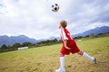 Kid, soccer ball and playing on green grass for sports, training or practice with clouds and blue sky. Young football Royalty Free Stock Photo