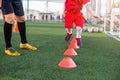 Kid soccer jogging and jump between cone marker with coach standing to coaching in soccer academy Royalty Free Stock Photo