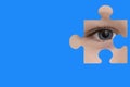 Kid spies through a blue puzzle. Symbol of autism awareness Royalty Free Stock Photo