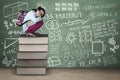 Kid squat on books with doodles in class Royalty Free Stock Photo