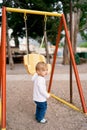 Kid stands on the playground near the swing Royalty Free Stock Photo