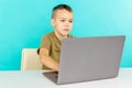 Kid studying online at home on the laptop in the blue room. Royalty Free Stock Photo
