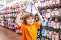 Kid in supermarket shoes shop. Sale, consumerism and people concept. Kids shoes store in supermarket, choosing kids in