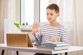 Kid with tablet computer sitting at table with books and having video call, virtual online leasson at home Royalty Free Stock Photo