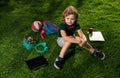 Kid with tablet device and school supplies sitting outdoor in garden, wearing short and shirt. Lttle child outdoor Royalty Free Stock Photo