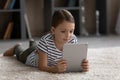 Happy tween girl child lying on carpet using digital touchpad Royalty Free Stock Photo