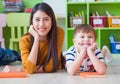 Kid and teacher looking at camera and smile lying down at school library. floor.kindergarden learning school