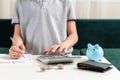 Kid teen boy counting money and taking notes, saving money in a piggy bank. Learning financial responsibility and Royalty Free Stock Photo