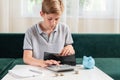 Kid teen boy counting money and taking notes, saving money in a piggy bank. Learning financial responsibility and Royalty Free Stock Photo