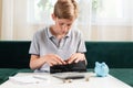 Kid teen boy counting money and taking notes, saving money in a piggy bank. Learning financial responsibility and Royalty Free Stock Photo