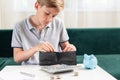 Kid teen boy counting money and taking notes, saving money in a piggy bank. Learning financial responsibility and Royalty Free Stock Photo