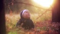 Kid throws yellow leaves in autumn park. The kid sits in leaves in the wood. The kid looks at yellow paduyushchy leaves