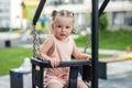 Kid toddler girl swinging on playground swing. Kid playing on school or kindergarten yard Royalty Free Stock Photo