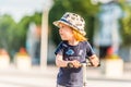 Kid toddler riding his scooter in a city. Summertime fun activity. Caucasian white boy is wearing a hat. Royalty Free Stock Photo