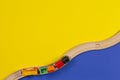 Toy train and wooden rails on yellow and blue color background Royalty Free Stock Photo