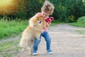 Kid training, playing with dog outdoors. Little girl takes the spitz in her arms. child hugging a pet. Happy baby is walking with Royalty Free Stock Photo