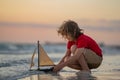 kid traveling on sea. Kid boy playing with toy boat in sea water. Happy holiday by the sea. Kid dreaming about sailing Royalty Free Stock Photo
