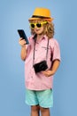 Kid traveller. Photo of cute child boy using mobile phone isolated over blue studio background. Portrait of kid tourist Royalty Free Stock Photo