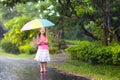 Kid with umbrella playing in summer rain. Royalty Free Stock Photo