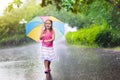 Kid with umbrella playing in summer rain. Royalty Free Stock Photo