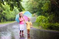 Kid with umbrella playing in summer rain.