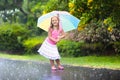 Kid with umbrella playing in summer rain.