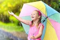 Kid with umbrella playing in summer rain. Royalty Free Stock Photo