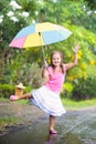 Kid with umbrella playing in summer rain.