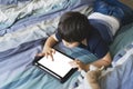 Kid using tablet for his homework, Child lying in bed playing game on digital touch pad in bed room,Young boy lying down with mock Royalty Free Stock Photo
