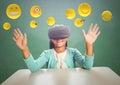 Kid in VR beneath emojis against green chalkboard Royalty Free Stock Photo