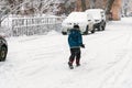 Kid walking in the snow next to parked cars